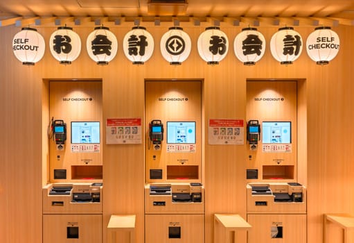 tokyo, japan - may 14 2024: Japanese self chekout corner in the Revolving Sushi Bar Kurasushi of Ginza decorated on the theme of summer matsuri festival with paper lanterns to appeal to tourists.