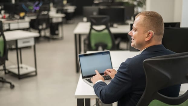 Caucasian deaf man typing on laptop in office