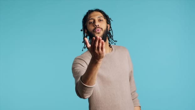 Middle Eastern frisky playful man blowing kisses to camera, being flirty. Lively charming BIPOC person having fun sending air kisses, doing romantic gesturing, studio background, camera A