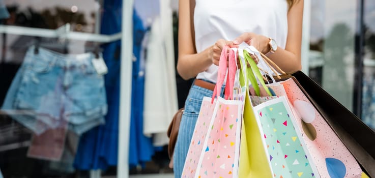 Shopping bags in the hands of a young woman on the city street. Sale and discount shopping concept.