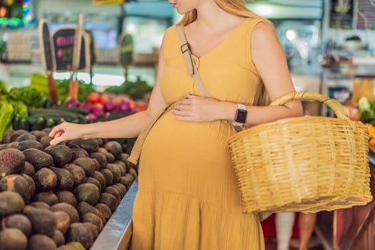 In a grocery store, a pregnant woman stands by a fruit stand, surrounded by various natural foods. She is in a public space where the local market offers whole foods for trade Pregnant woman buying organic vegetables and fruits at Mexican style farmers market