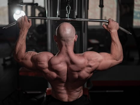 Caucasian man doing lat pull-downs on a machine