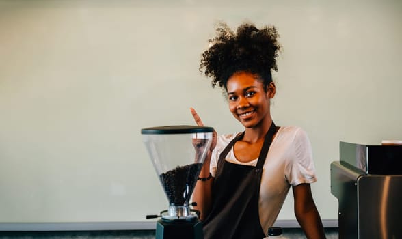 At the cafe a confident black woman stands at the counter. Portrait of owner a successful businesswoman in uniform smiling with satisfaction ensuring customer service. Inside a small business cafe