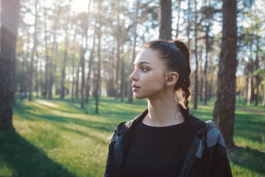 Tranquil young woman in profile takes in the beauty of the setting sun amidst tall pine trees