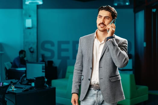Young arab businessman working at modern office, talking on mobile phone close up