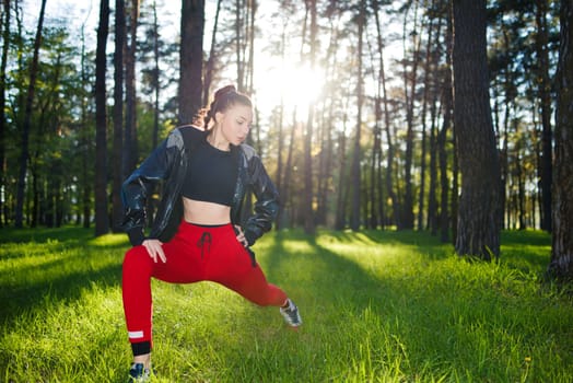 Young woman in tracksuit doing leg stretches in a park in early spring.