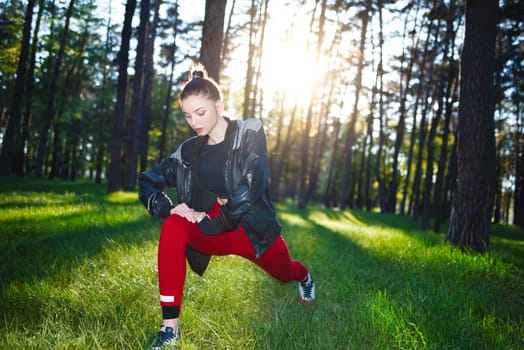 Athletic woman in tracksuit doing outdoor exercises in a park.