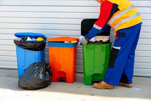 Janitor takes garbage out of trash container outdoors in the street