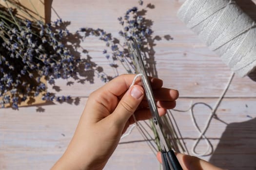 Woman creating bouquets of dry lavender flowers. Process of making scented bouquets and sachet from home grown herbs. Step by step alternative medicine. DIY