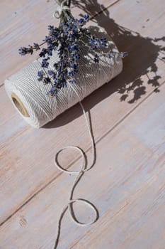 Lavender flowers next to white cotton rope on wooden background. Aromatherapy and organic concept. Still life of dried lavender herbs. Eco sustainable concept