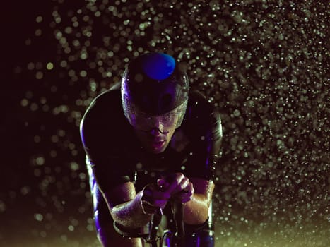 A triathlete braving the rain as he cycles through the night, preparing himself for the upcoming marathon. The blurred raindrops in the foreground and the dark, moody atmosphere in the background add to the sense of determination and grit shown by the athlete