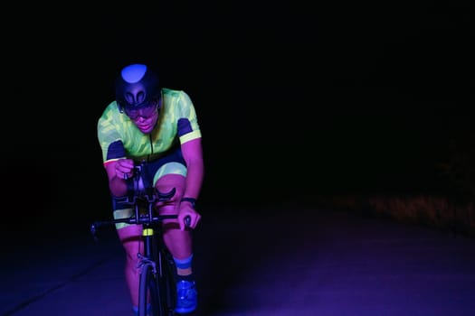 A triathlete rides his bike in the darkness of night, pushing himself to prepare for a marathon. The contrast between the darkness and the light of his bike creates a sense of drama and highlights the athlete's determination and perseverance