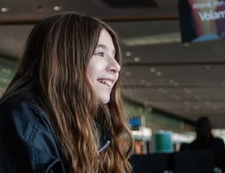 Teenager looks out of airport window as she waits for her plane to depart