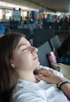 Young woman waiting for her plane to leave, sleeping a bit in the airport terminal