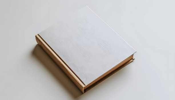 A rectangular white book with a wooden spine is elegantly placed on a white table. The combination of wood, metal, and transparent font give it a fashionable accessory vibe