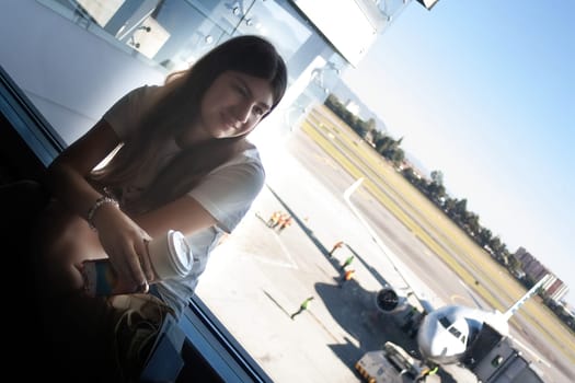 Teenager waits for her plane to depart drinking coffe