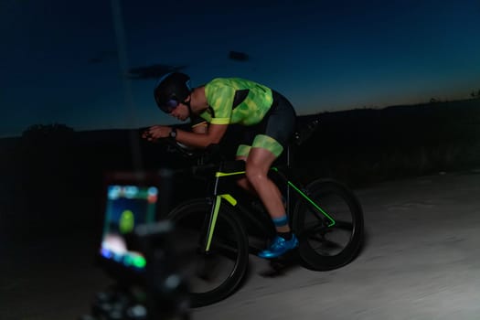 A videographer recording a triathlete riding his bike preparing for an upcoming marathon.Athlete's physical endurance and the dedication required to succeed in the sport