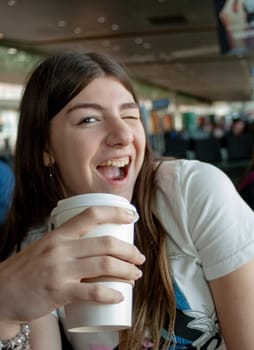 Teenager drinking coffee with a happy expression during a stopover at an international airport