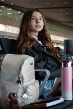 Girl with her luggage, book and pet on an international airport stopover