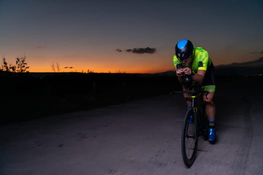 A triathlete rides his bike in the darkness of night, pushing himself to prepare for a marathon. The contrast between the darkness and the light of his bike creates a sense of drama and highlights the athlete's determination and perseverance