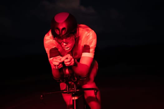 A triathlete rides his bike in the darkness of night, pushing himself to prepare for a marathon. The contrast between the darkness and the light of his bike creates a sense of drama and highlights the athlete's determination and perseverance