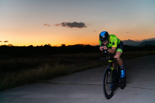 A triathlete rides his bike in the darkness of night, pushing himself to prepare for a marathon. The contrast between the darkness and the light of his bike creates a sense of drama and highlights the athlete's determination and perseverance