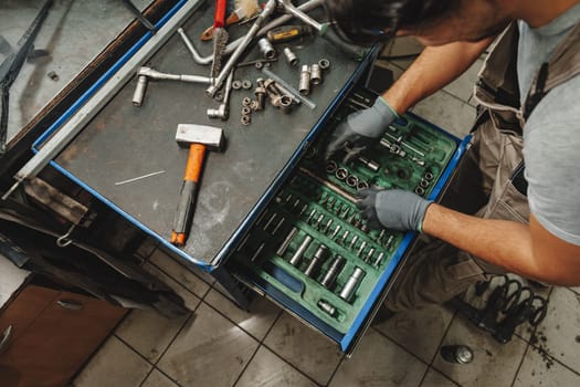 Male technician standing near tool table in car service close up