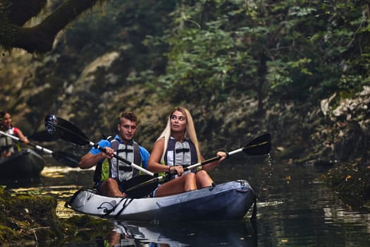 A group of friends enjoying having fun and kayaking while exploring the calm river, surrounding forest and large natural river canyons.