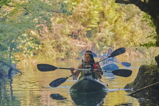 A group of friends enjoying having fun and kayaking while exploring the calm river, surrounding forest and large natural river canyons.