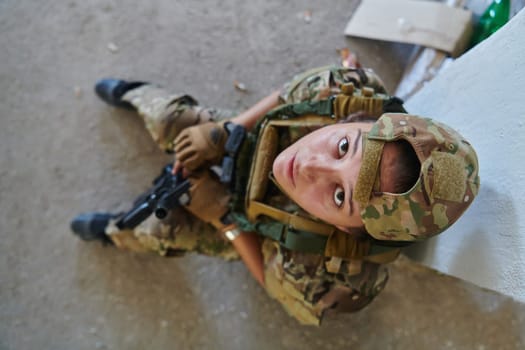 A woman in a professional military uniform sits in an abandoned building, ready for a dangerous mission, exuding bravery and determination.