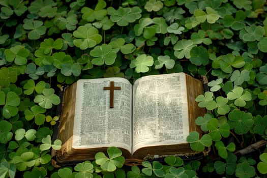 a bible book and a cross lying on the green clover leaves..