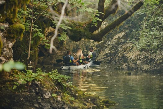 A group of friends enjoying having fun and kayaking while exploring the calm river, surrounding forest and large natural river canyons.