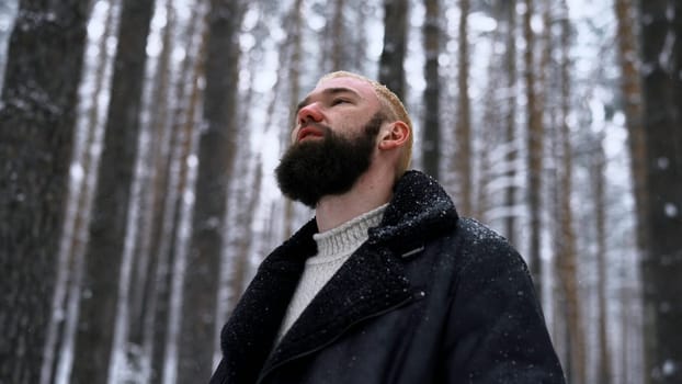 Lone man walking through snow. Media. Young guy with snow on his jacket feeling alone and isolated in cold forest