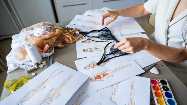 Faceless woman draws underwear sketches. Close-up of fashion designer's hands with lace bra