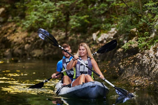 A young couple enjoying an idyllic kayak ride in the middle of a beautiful river surrounded by forest greenery.