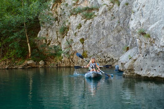 A group of friends enjoying having fun and kayaking while exploring the calm river, surrounding forest and large natural river canyons.