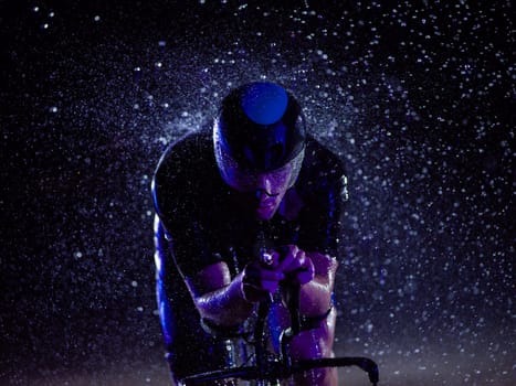 A triathlete braving the rain as he cycles through the night, preparing himself for the upcoming marathon. The blurred raindrops in the foreground and the dark, moody atmosphere in the background add to the sense of determination and grit shown by the athlete