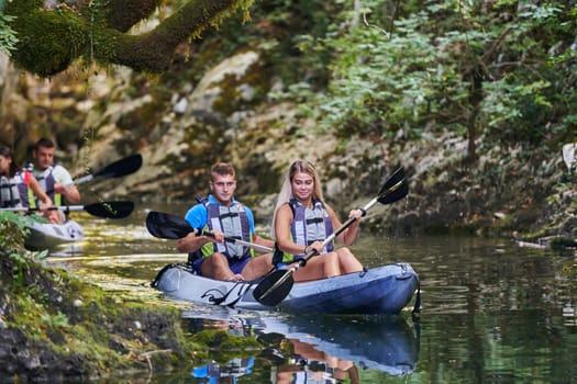 A young couple enjoying an idyllic kayak ride in the middle of a beautiful river surrounded by forest greenery.