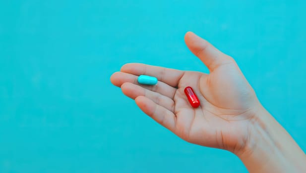 Hand holding red and blue pills against a blue background