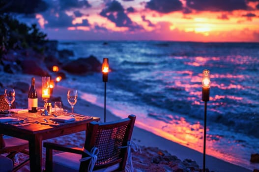 A table set for a romantic dinner on the beach with torches lit, waves gently crashing, and a stunning sunset.