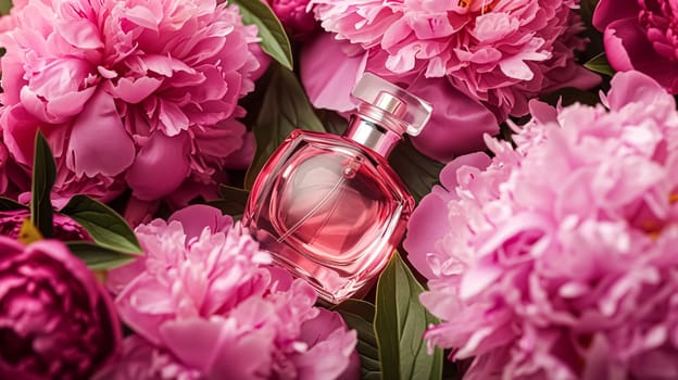 Perfume bottle in flowers, fragrance on blooming background, floral scent and cosmetic product idea