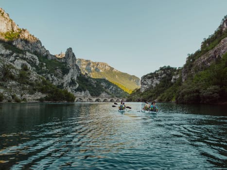 A group of friends enjoying having fun and kayaking while exploring the calm river, surrounding forest and large natural river canyons.