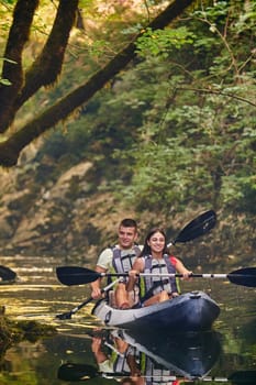 A young couple enjoying an idyllic kayak ride in the middle of a beautiful river surrounded by forest greenery.