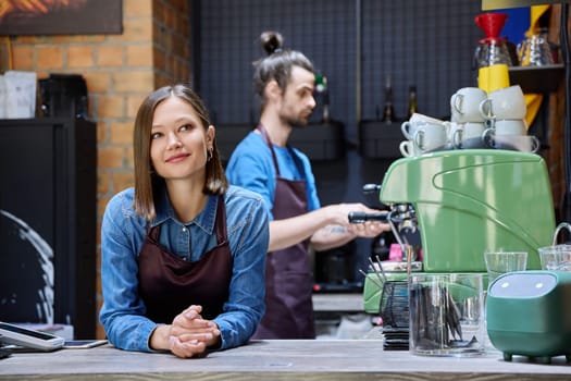 Business team colleagues partners young man woman in aprons working together in workplace behind counter in restaurant coffee shop cafeteria. Cooperation staff partnership teamwork work small business