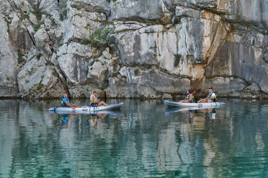 A group of friends enjoying having fun and kayaking while exploring the calm river, surrounding forest and large natural river canyons.