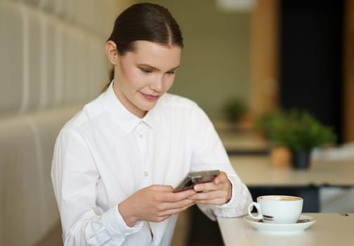 Beauty businesswoman using phone sitting alone in a chic cafeteria