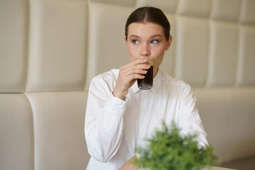 Portrait of a caucasian adult beauty woman in elegant clothes sipping black coffee in a cafeteria