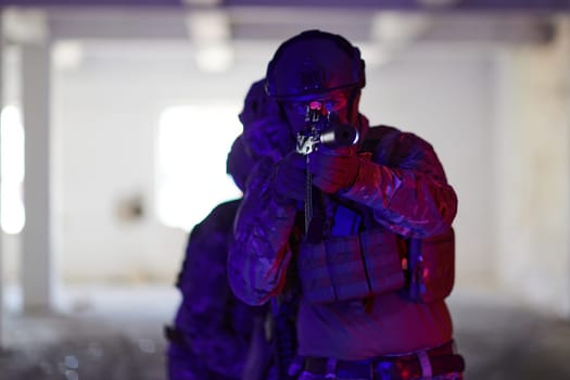 A professional soldier undertakes a perilous mission in an abandoned building illuminated by neon blue and purple lights.