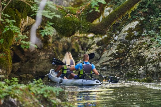 A young couple enjoying an idyllic kayak ride in the middle of a beautiful river surrounded by forest greenery.