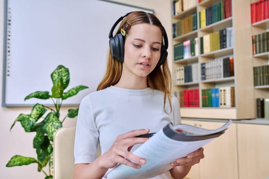 Webcam view of teenage girl, high school student, in headphones, talking to camera. Female teenager studying remotely, video conference chat, online test exam lesson. Technology education adolescence